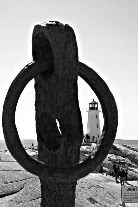 Schwarzweiß-Fotografie: Der Blick durch die Öse eines uralten Ankers gibt einen Rahmen um den Leuchtturm von Peggy's Cove einmal anders einzufangen.